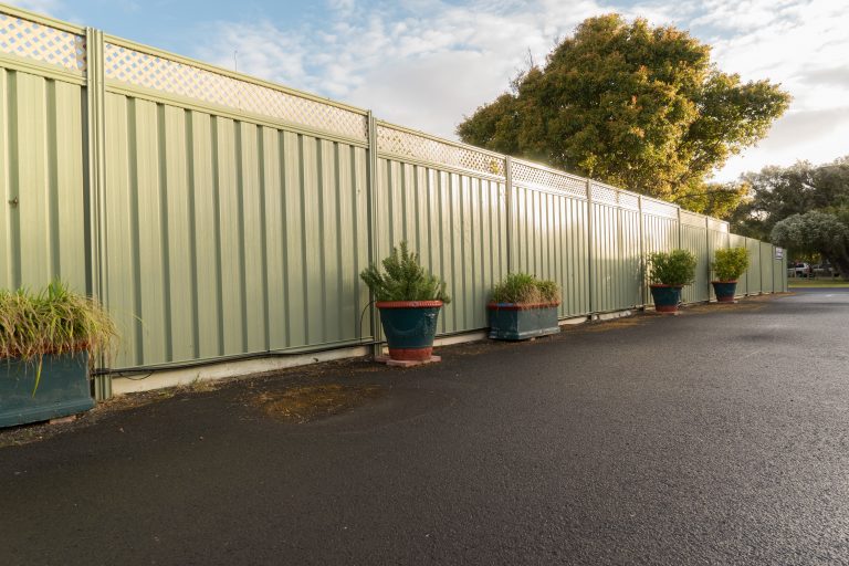 Green fence and wet asphalt road on garden